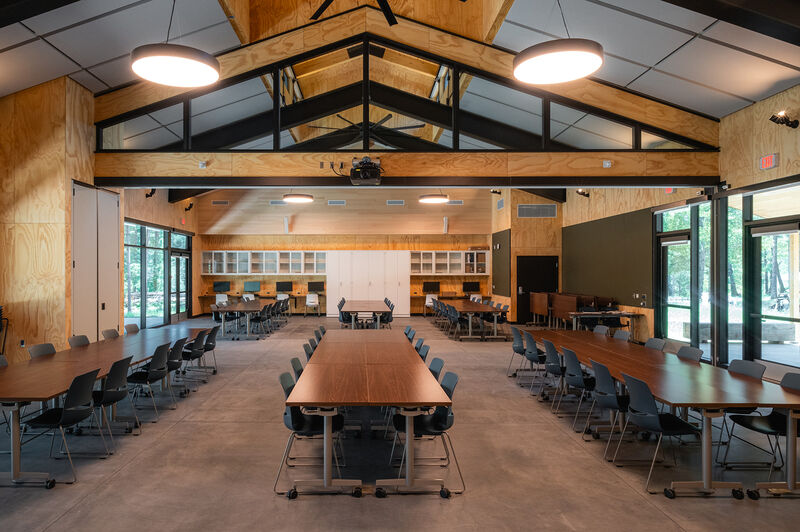 Enchanted Hills meeting room with wooden tables and chairs, high ceiling with exposed beams, and large windows.