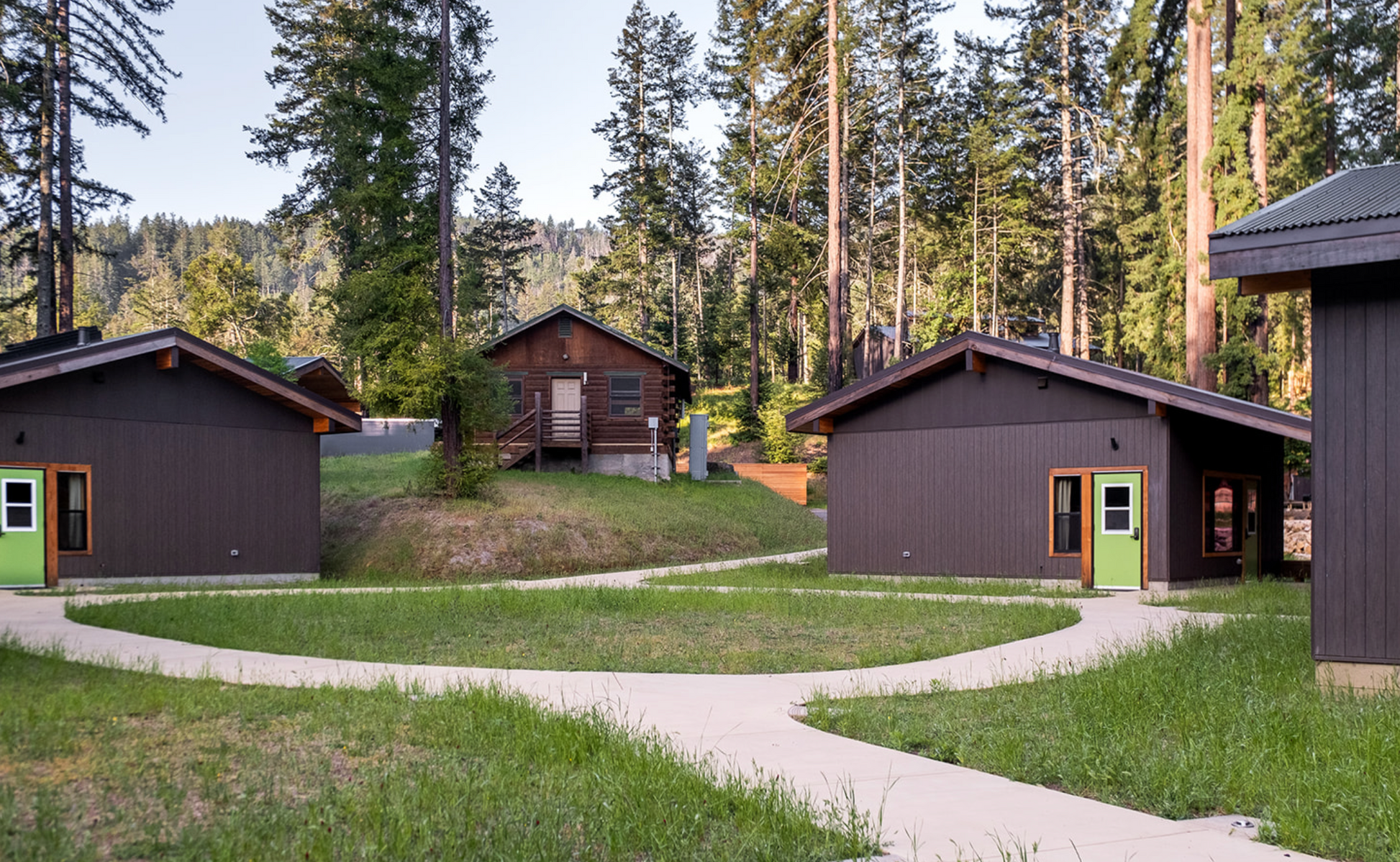 Group of bunkhouse cabins in a forest setting with a pathway.