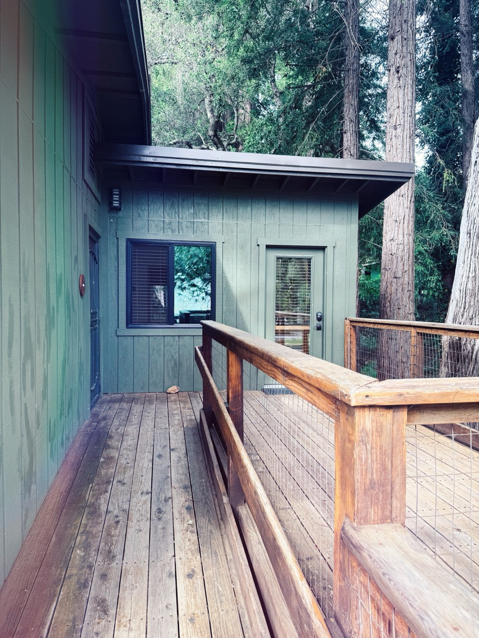 Enchanted Hill Lodge with wooden deck and railing surrounded by trees