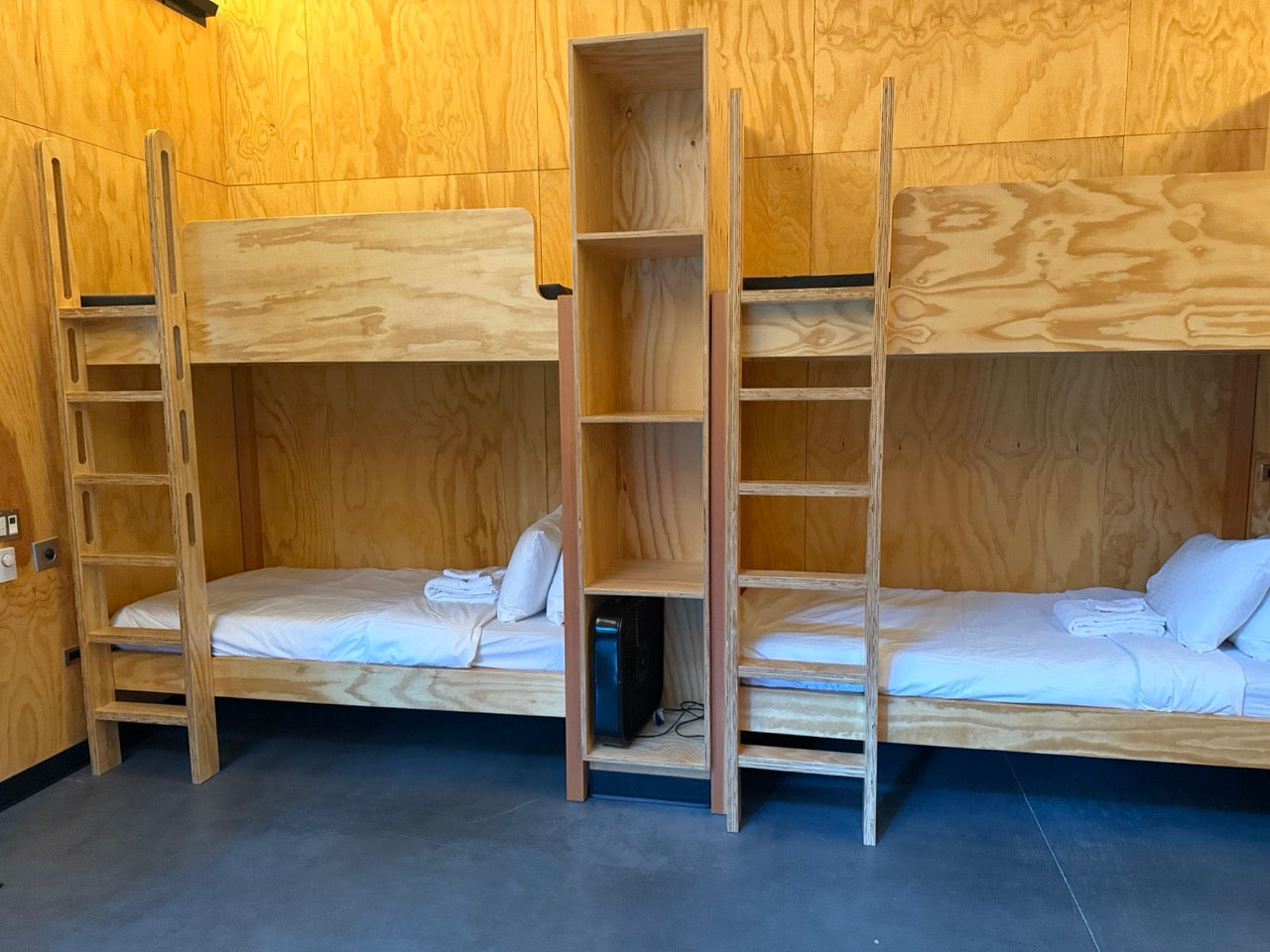 Wooden bunk beds with shelves in the bunkhouse.