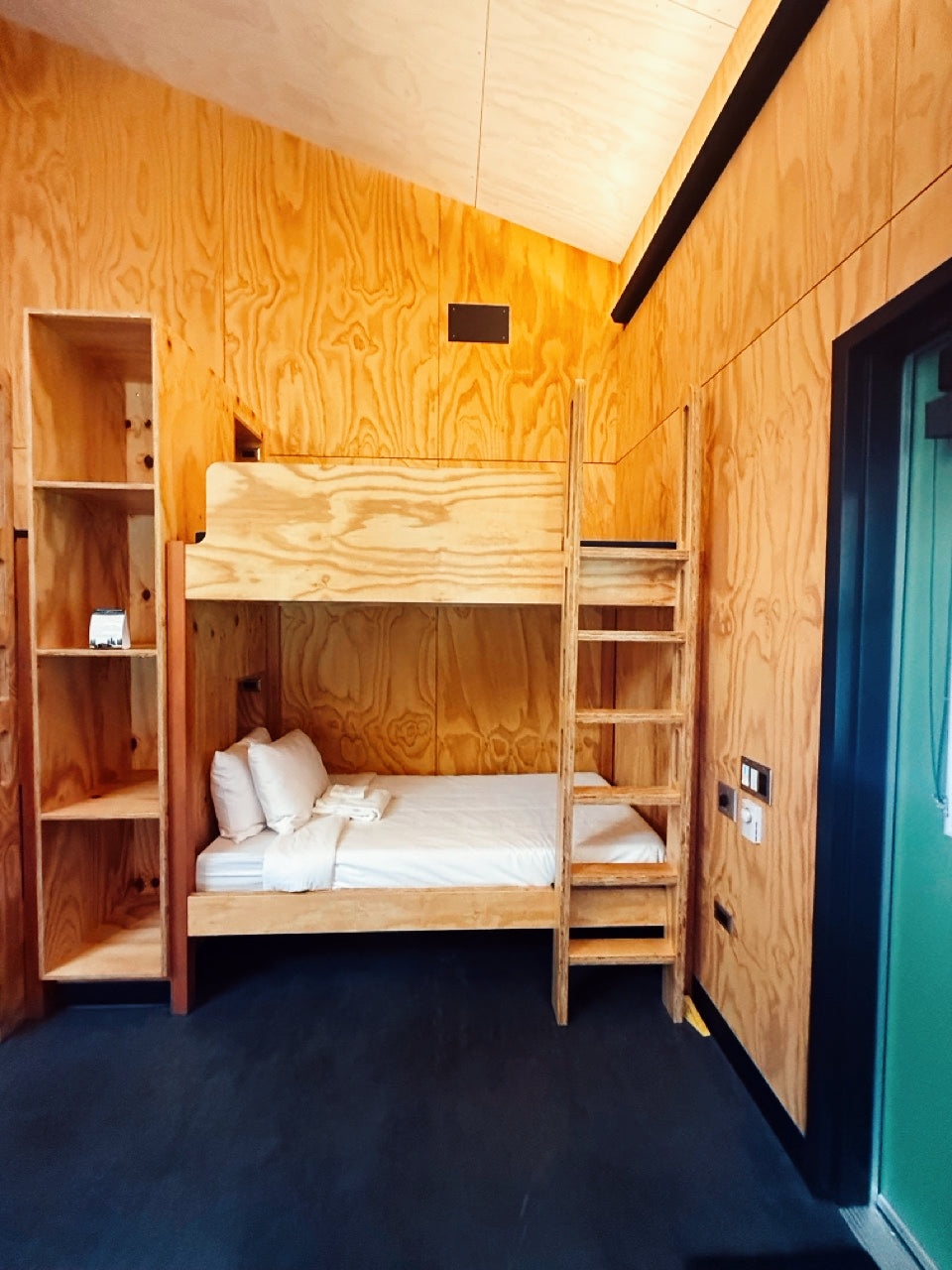 Wooden bunk bed in a bunkhouse with wooden walls and a blue floor.