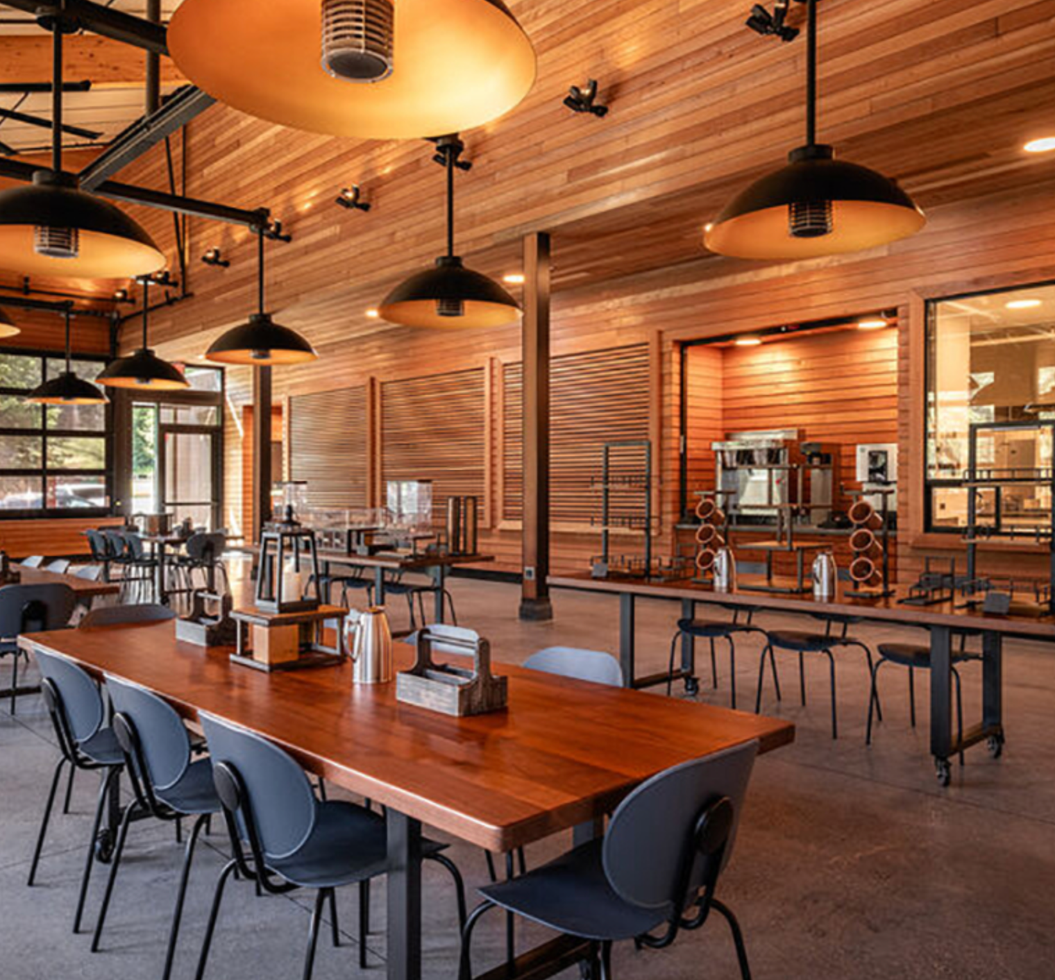The dining hall at Enchanted Hills with wooden tables, chairs, and pendant lights.