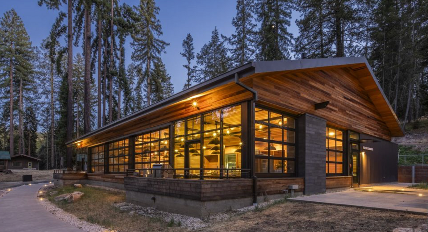 Exterior of the dining hall with large windows surrounded by trees at dusk