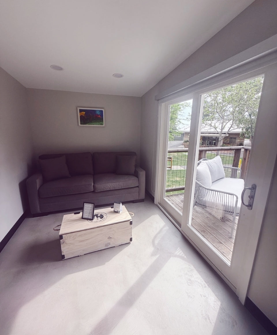 Living room in a Lakeside Cabin with a gray sofa, wooden coffee table, and sliding glass door leading to a deck.