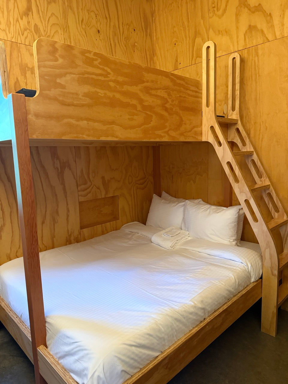Wooden bunk bed with white bedding in the Bunkhouse with wooden walls.